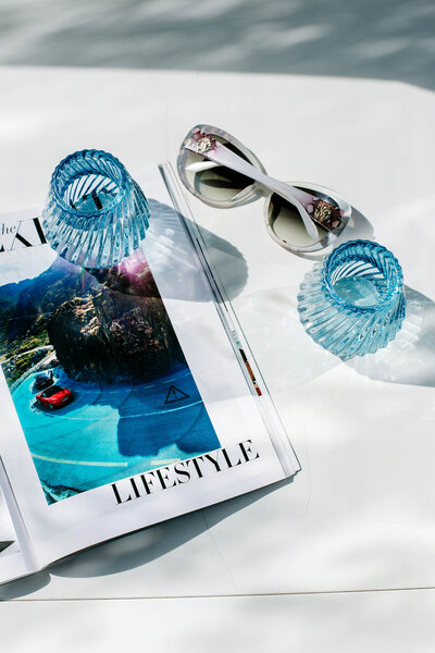 Straw beach tote, earrings and bikini next to luxury pool