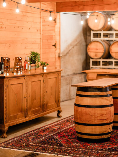 Rustic wooden bar setup with wine barrels and string lights