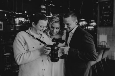 Jana Sauer Weddings zeigt einem Hochzeitspaar die Fotos