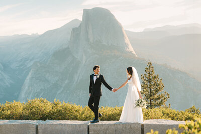 Couple standing at the cliffside edge in Yosemite during their sunset elopement