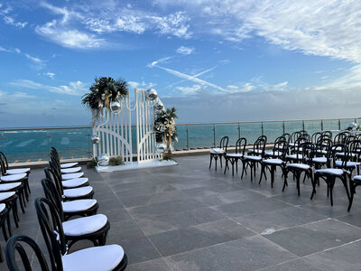 A picturesque destination wedding ceremony by the ocean, with rows of chairs facing the beautiful seaside view.