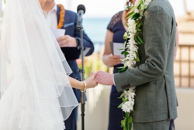 A close up of two people holding hands during their wedding ceremony 