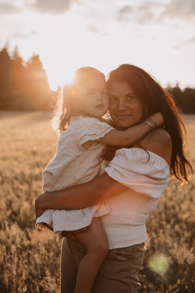 Moeder met kindje in haar armen tijdens golden hour in de natuur bij de Kalmhoutse Heide.