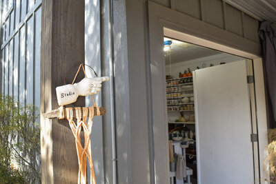 A ceramic hand with the word "studio" glazed on it points in the direction of the door of Jill's Key West, FL and Laingsburg, MI studio