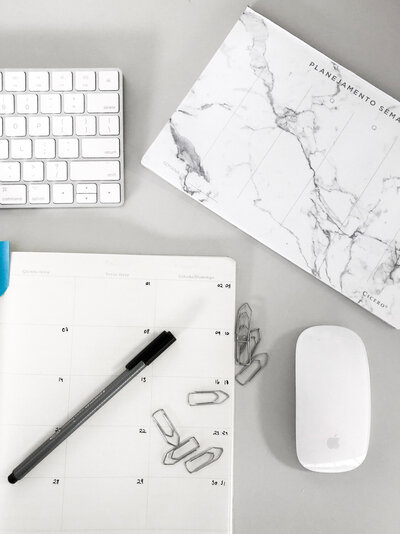 Flat lay of office supplies, including a calendar, pen, and computer mouse