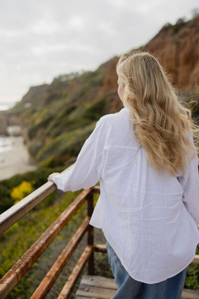 Brogan standing against an outdoor railing looking out to the beach