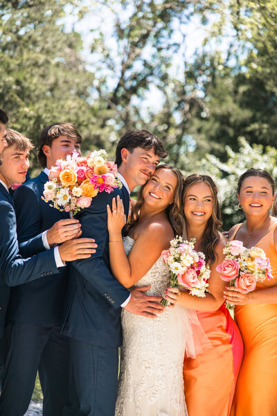 Bridal party in colorful dresses smiling outdoors at Hidden Vineyards in Maize, KS, during wedding celebration