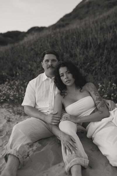 man and woman sitting on ground and leaning into each other