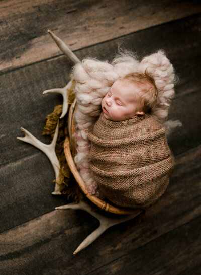 A sleepy baby girl gets her photo taken while laying amongst deer sheds.