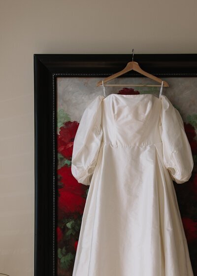 Wedding dress hanging on large picture frame by idaho wedding photographer erica rochelle photography logo