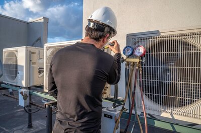 Technician performing HVAC maintenance on rooftop unit. 
