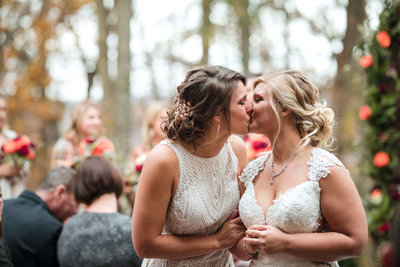 two brides kiss at wedding ceremony