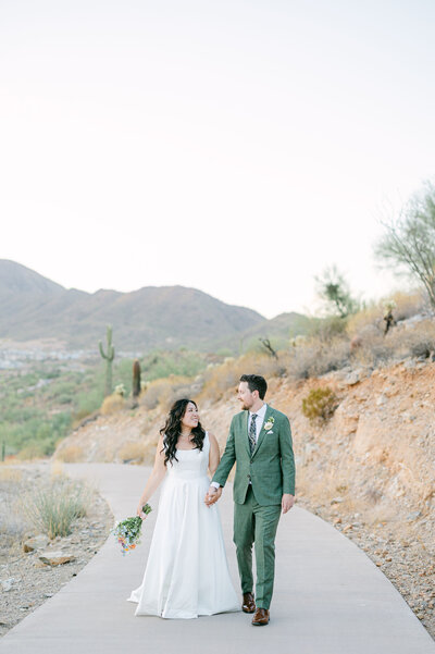 The bride and groom, hand in hand, stroll along a picturesque path at the Adero Scottsdale venue, capturing the beauty of their journey together