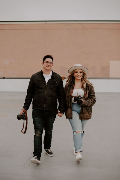 photo of male and female photographers holding hands and walking together