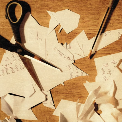 view of scissors and cut paper on wood table with pen 
