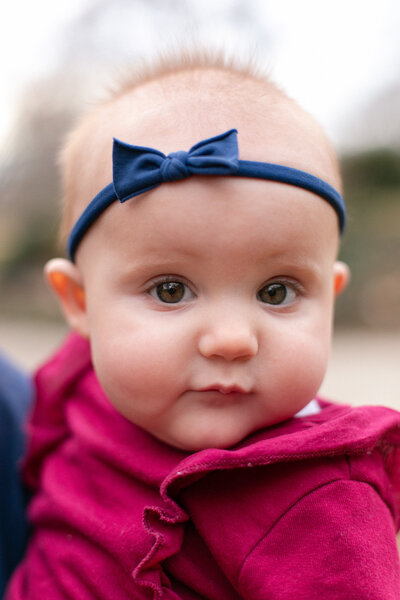 6 month old baby girl with burgundy onesie and navy bow