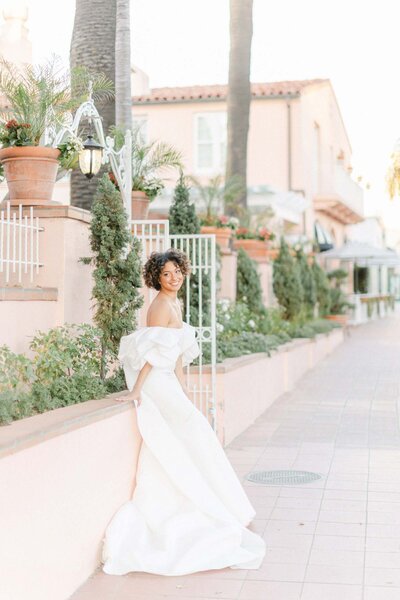 Bride leaning on balcony surrounded by palm trees and ferns