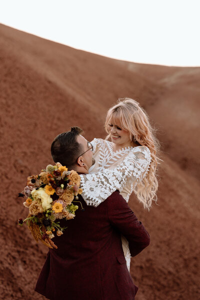 Groom holding up bride at Painted Hills in Central Oregon.