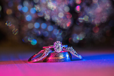 Artistic wedding rings with blue and pink lighting.