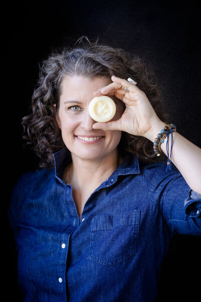woman holds a natural hand-made soap in front of her face