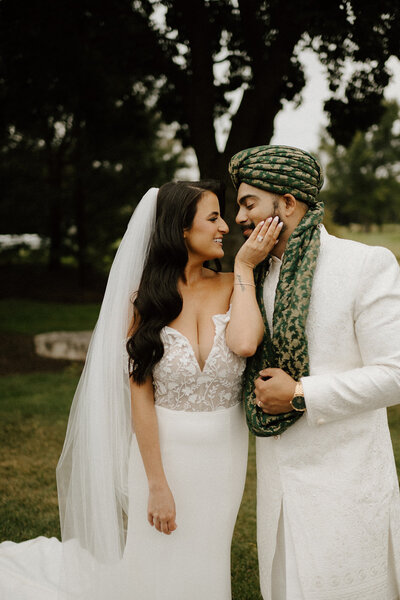 Bride and Groom smile at each other on wedding day outdoors after ceremony