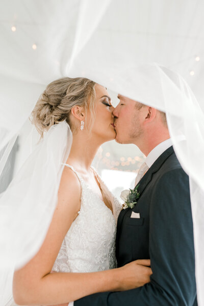 Groom kissing bride on the cheek at classic wedding