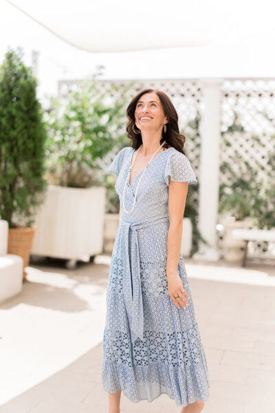 A woman in a long blue dress looks carefree and happy