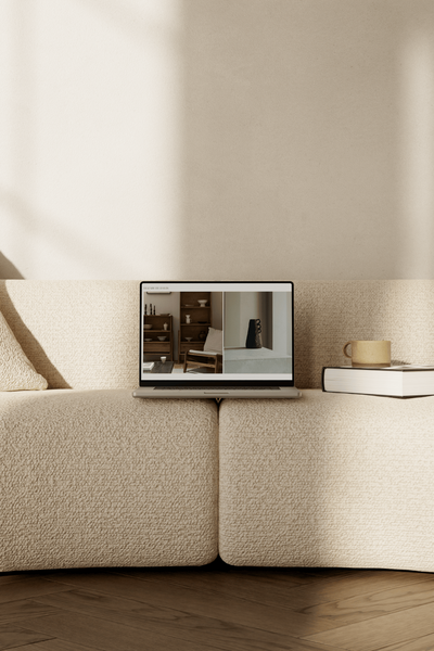 A laptop rests on a beige bouclé sofa, its screen showing the title page of Elizabeth Davis's Client Handover Guide.