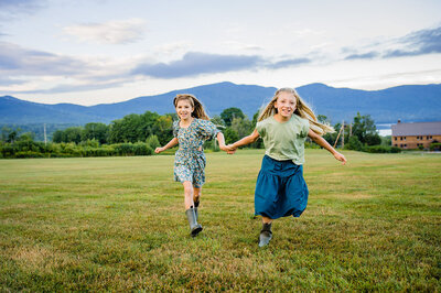 two sisters holding hands and running at mountain top inn in chittenden vermont
