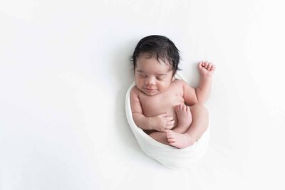 Minimalistische fotoshoot aan huis met een lichte achtergrond. Leg de unieke details van je baby vast in een rustige en natuurlijke omgeving.