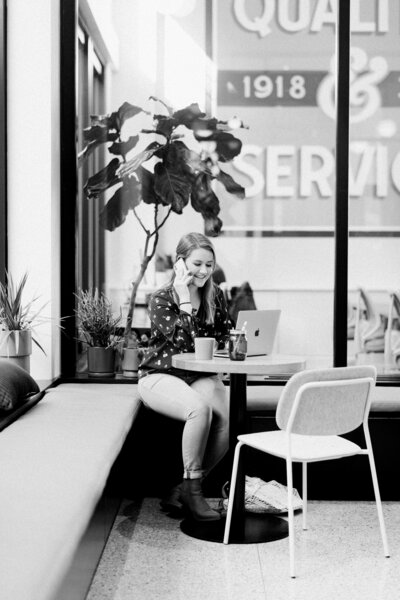 Woman on the phone with a laptop on the table at a cafe