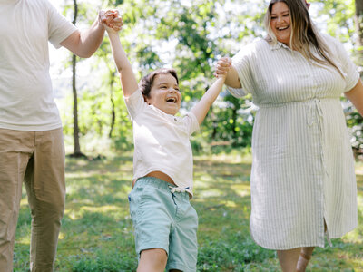 Shalae's family with closeup of son Renner in cream shirt and blue shorts being swung by mom and dad