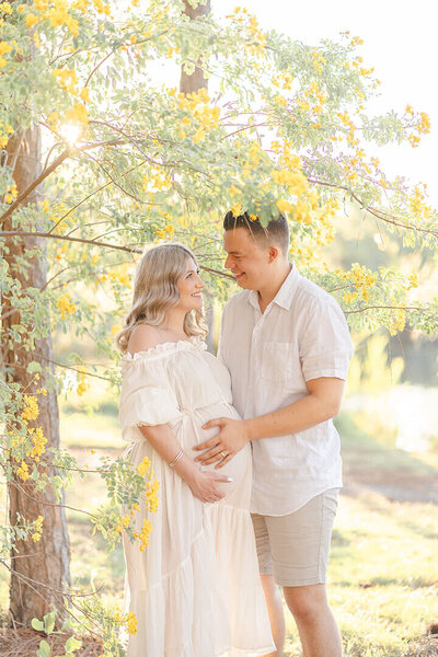 Woman in Hazel and Folk Emmaline gown having bump photos with family in yellow flowers in Brisbane.