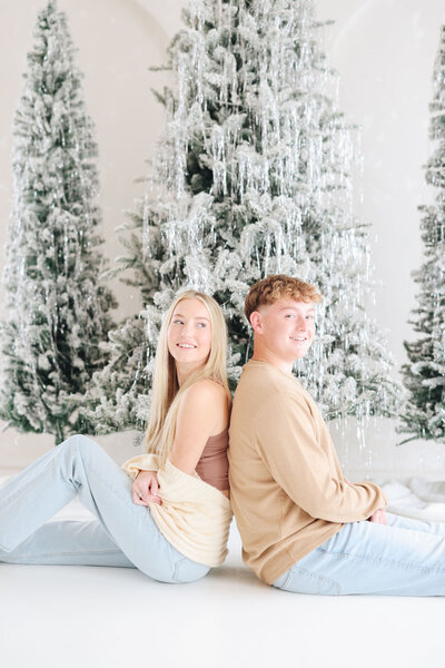 Siblings posing in front of Christmas trees