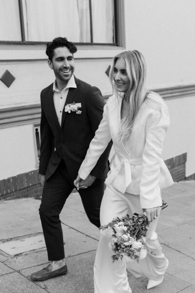 newlyweds walking on city sidewalk