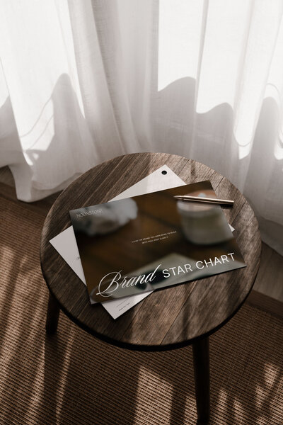 Flat lay of brand strategy documents and creative direction guide on a wooden table, part of the Moonstone Brand Star Chart process.