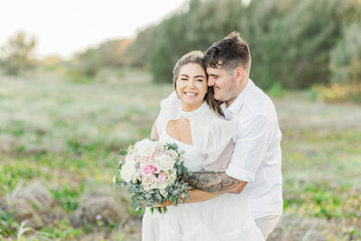 groom squeezes bride and makes her laugh during bridal portraits