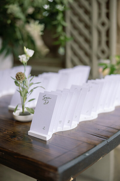 Modern white  escort card display with green brush lettering for Glen Manor House wedding