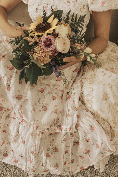 close up of a woman in a floral dress holding a flower bouquet