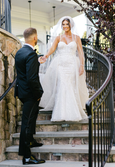 bride and groom on stairs holding hands