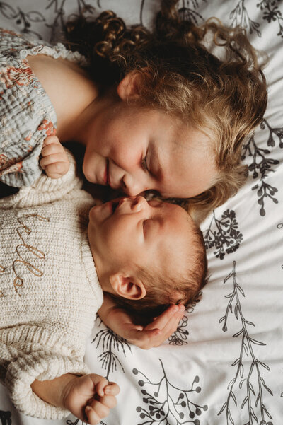 Big sister snuggles with her little brother during his newborn in-home photoshoot in Lincoln, ND