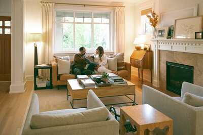 Family sitting together on the sofa reading a book during a lifestyle at-home family photography session in Orange County.