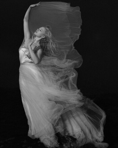 Fine art wedding photography in Scotland Bride stands tall arms up as the wind blows her dress