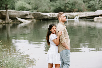 Couple taking engagement photos by waterfall at Mckinney Falls