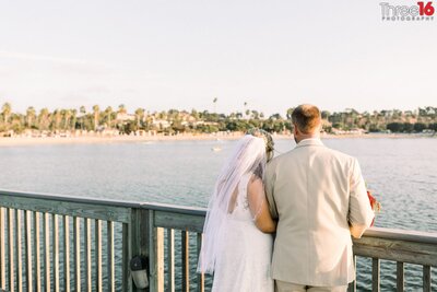 Bride and Groom look out over the waters at Newport Dunes wedding venue