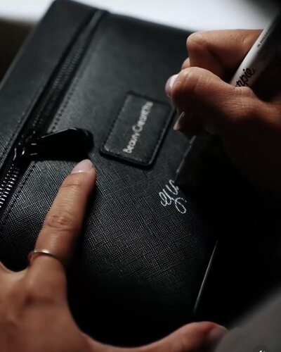 Custom calligraphy services on a black leather cosmetic case