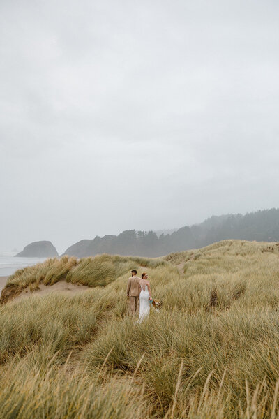 Couple walks along the sand dunes during their oregon coast elopement.