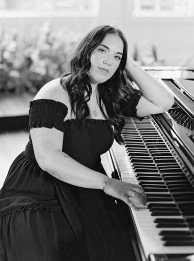 Black and white photo of Mikaela Kahn live wedding vocalist leaning on her piano