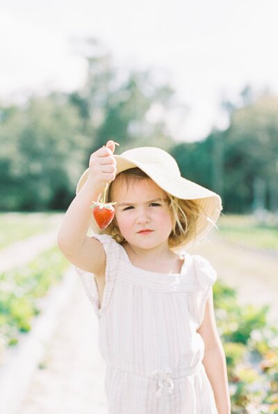 little girl holding strawberries from manual mode for moms course
