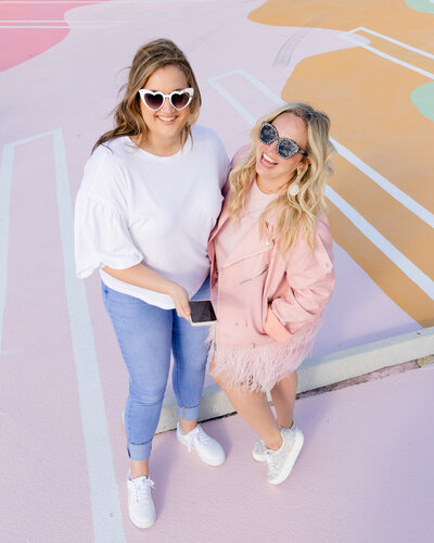 Katie and Natalie from Love Social Media posing on painted concrete